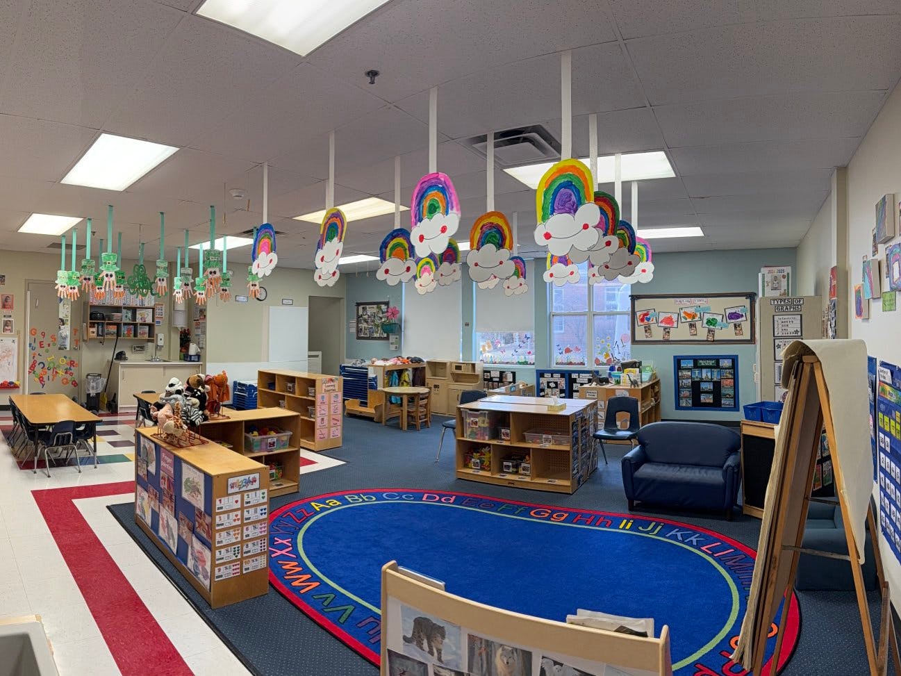 An empty classroom with rainbow and paper chain decorations hanging from the ceiling