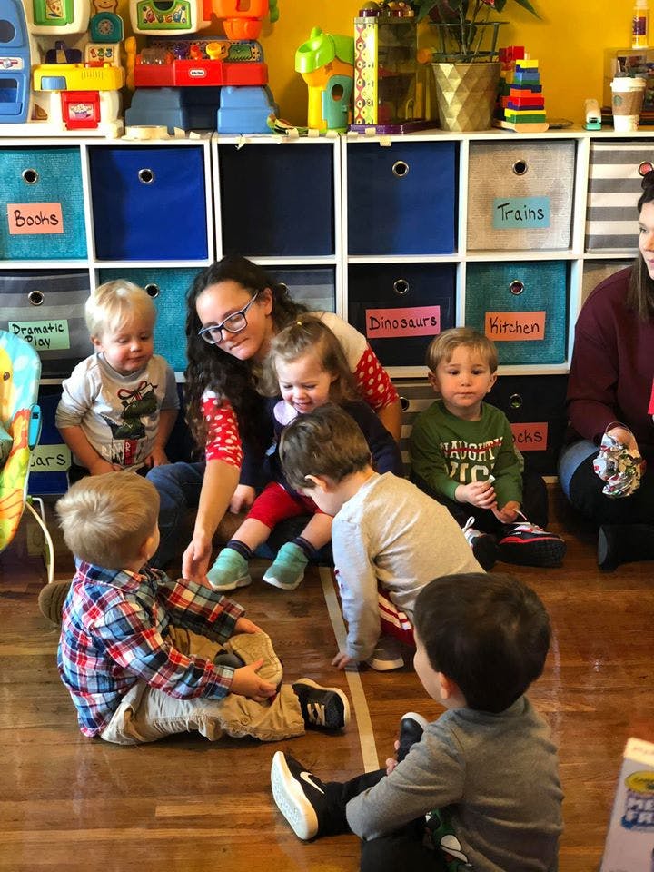 Adult and children sitting on the floor in a classroom