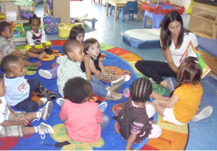 Adult reading to children sitting on a colorful rug