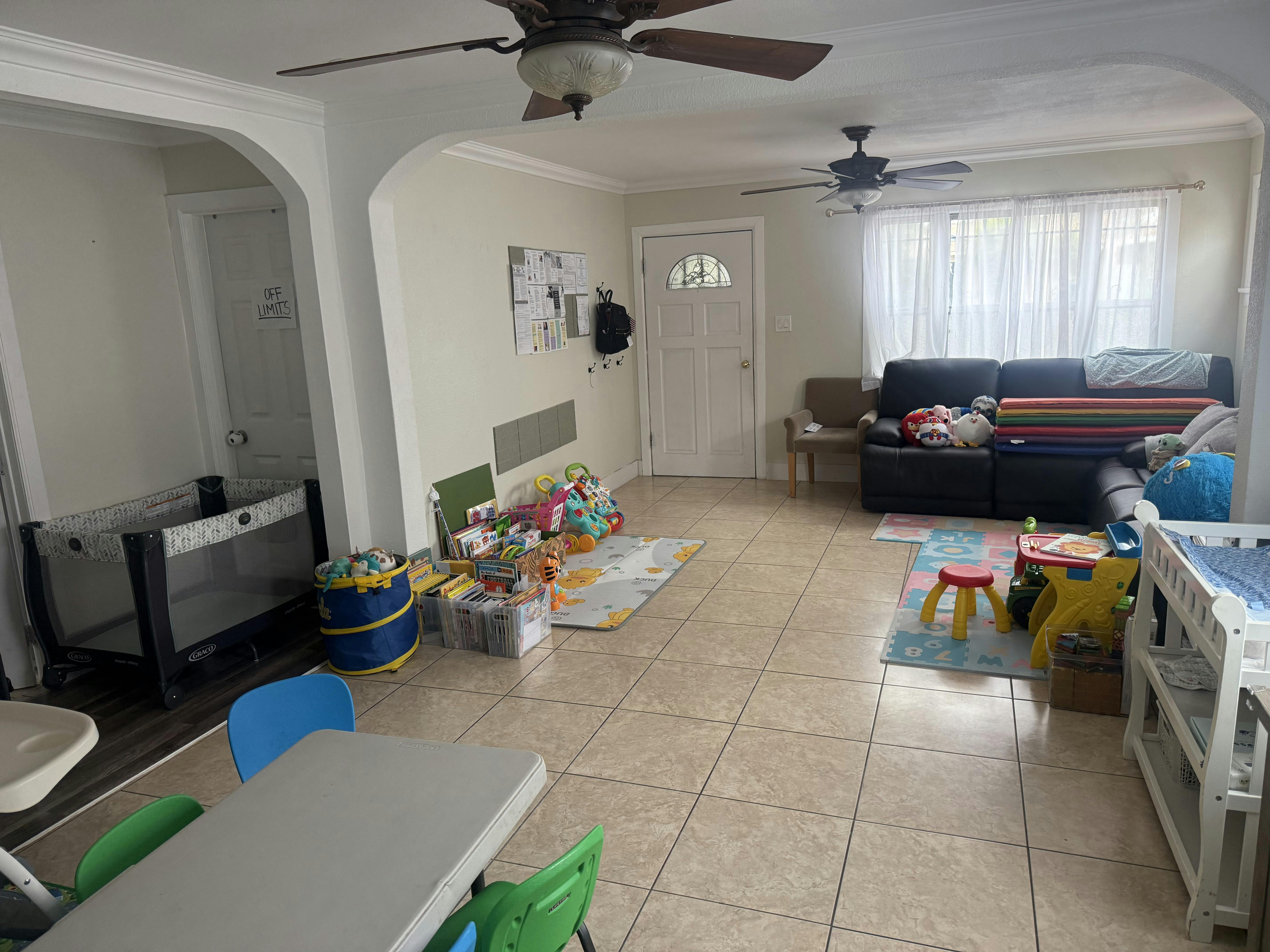 A living room with a playpen, children's toys and books, and a sofa
