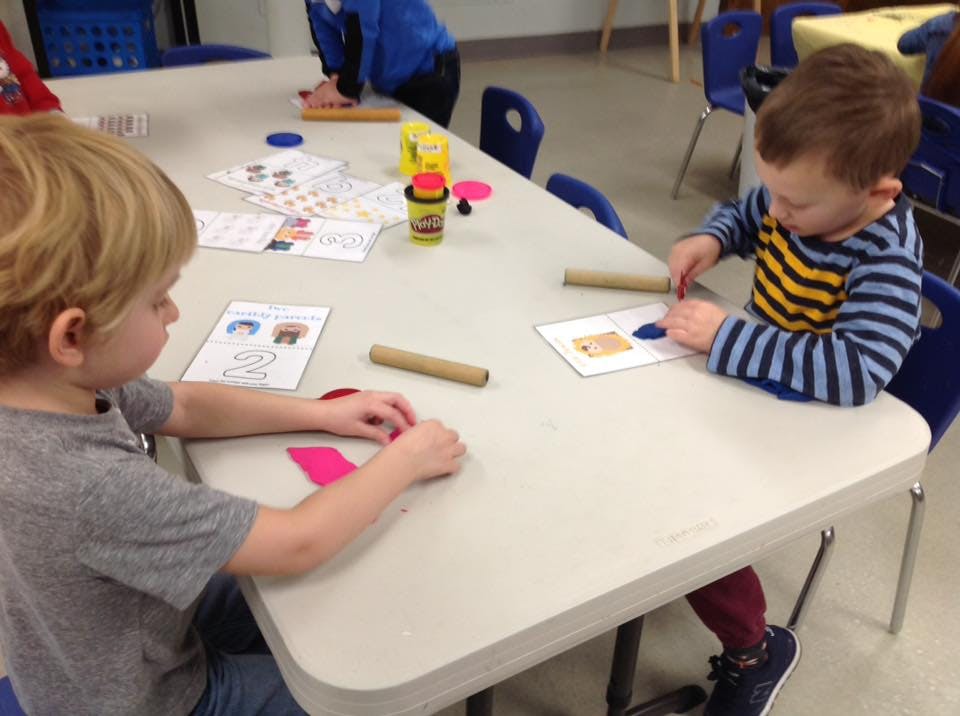 Two children playing with playdough at a table