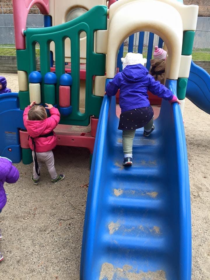 Child climbing up a blue slide on a playground