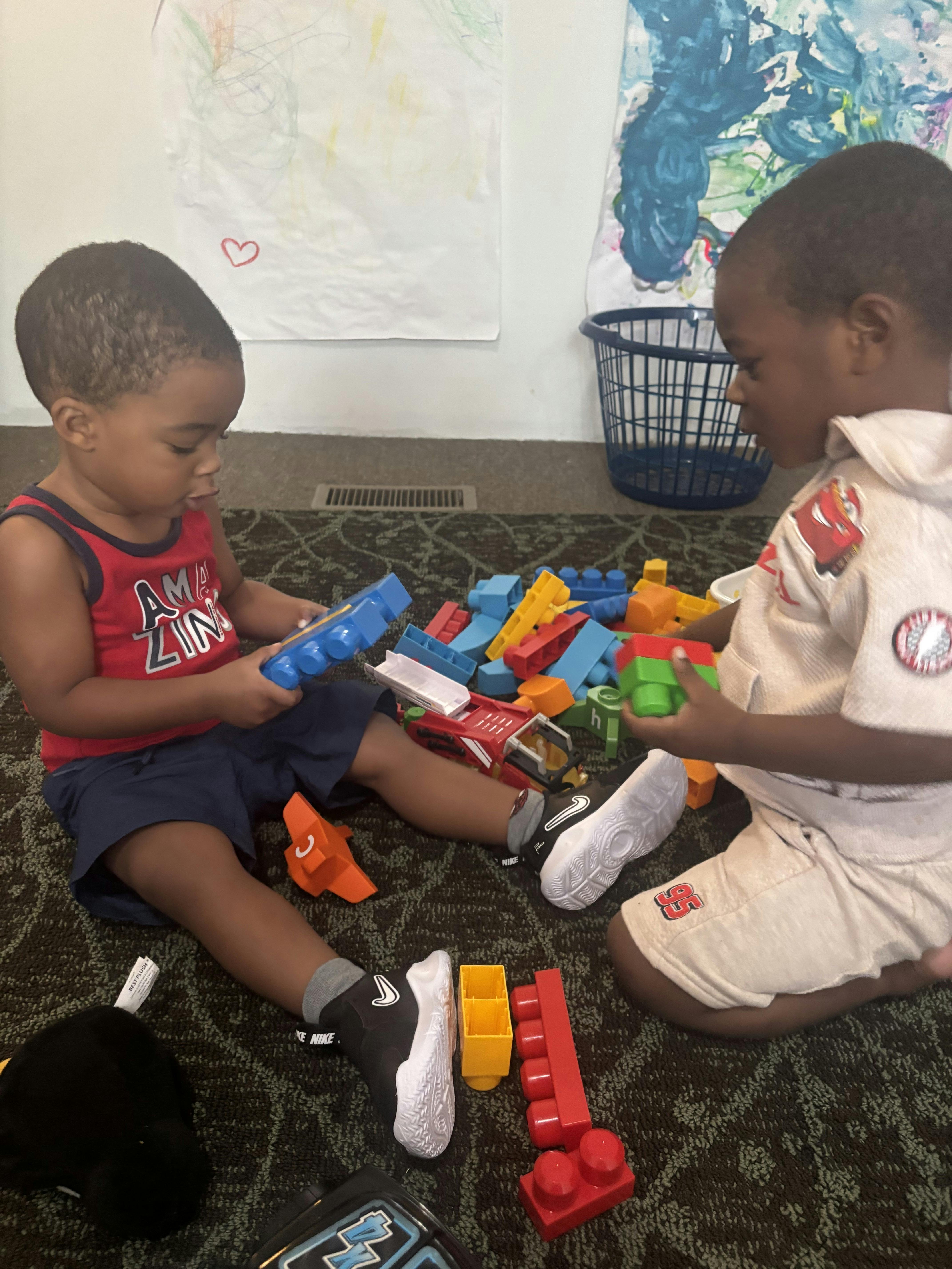 Two children sitting on the floor playing with colorful building blocks