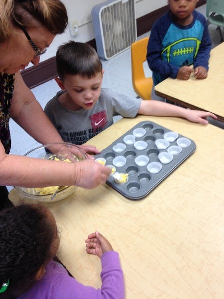 Adult and child filling a muffin tin with batter