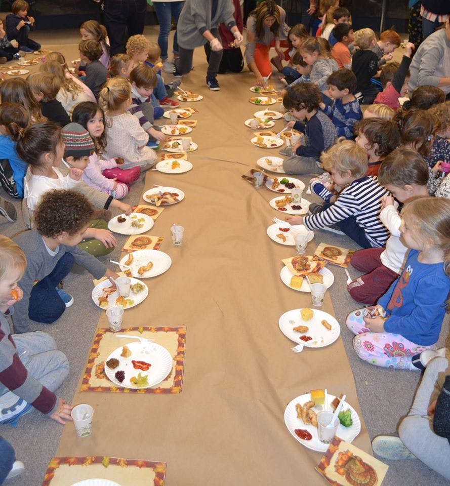 Children sitting on the floor eating food from plates