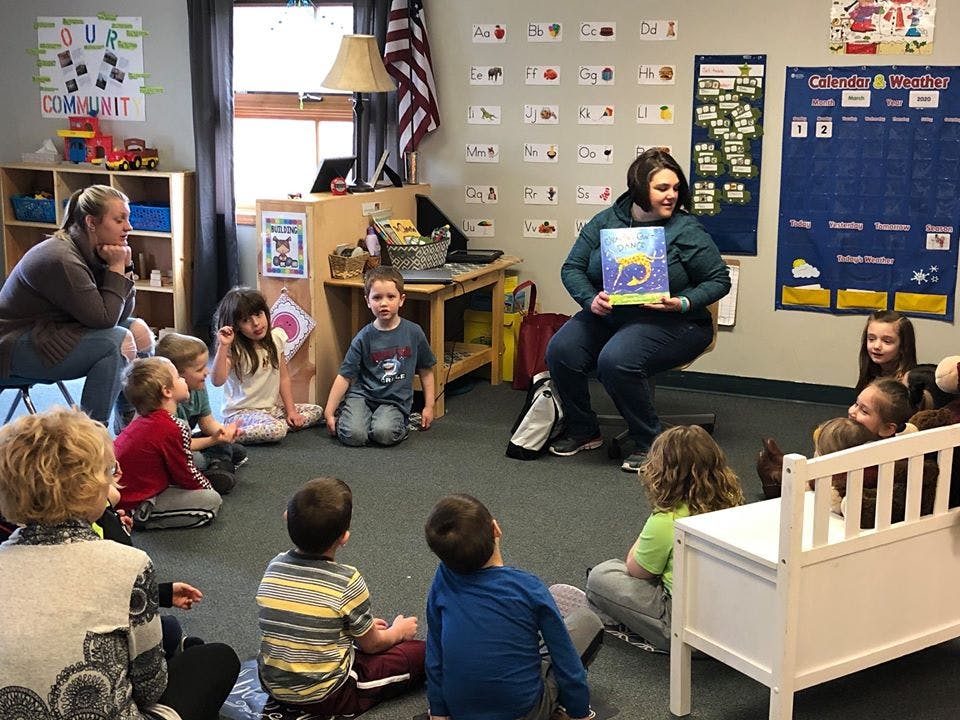 Adult reading a book to children in a classroom
