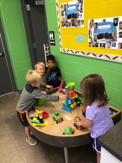 Children playing with sand and toys at a sand table