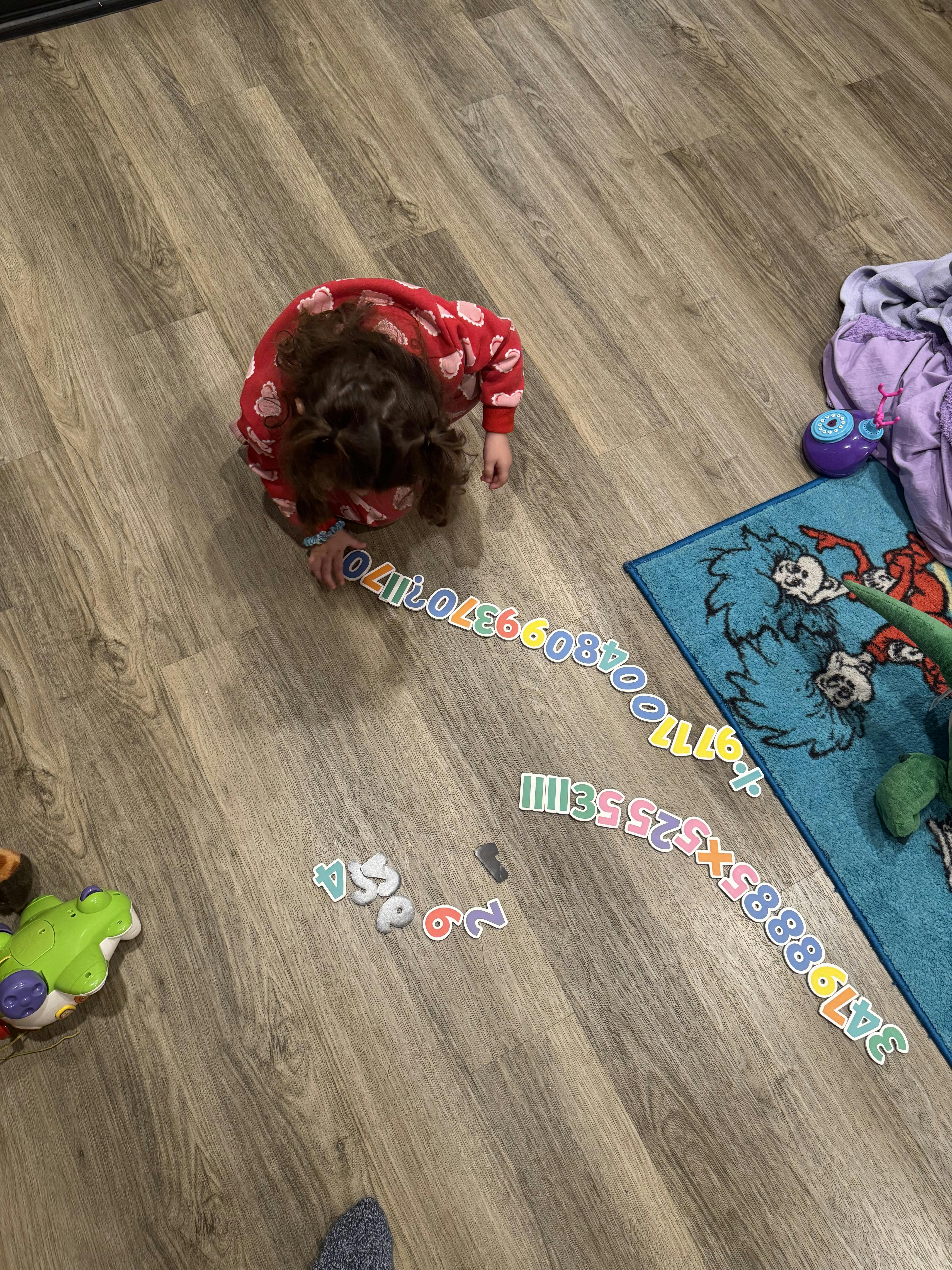 Child playing with number puzzle pieces on a floor