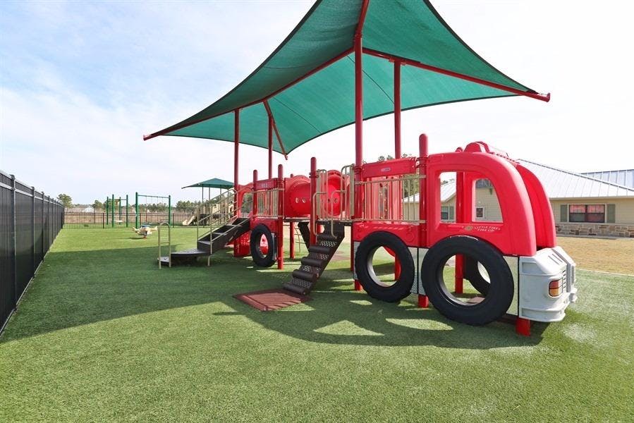Playground with a red fire truck structure and green shade canopy