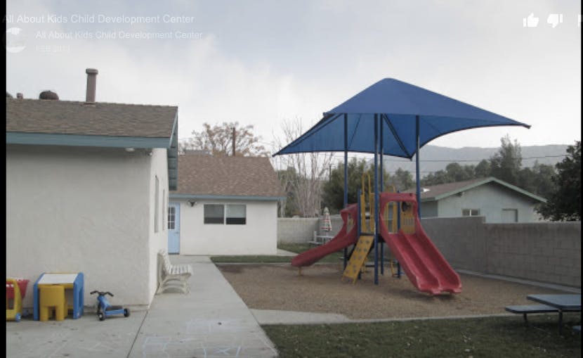 Playground with slides and a blue shade structure next to a building