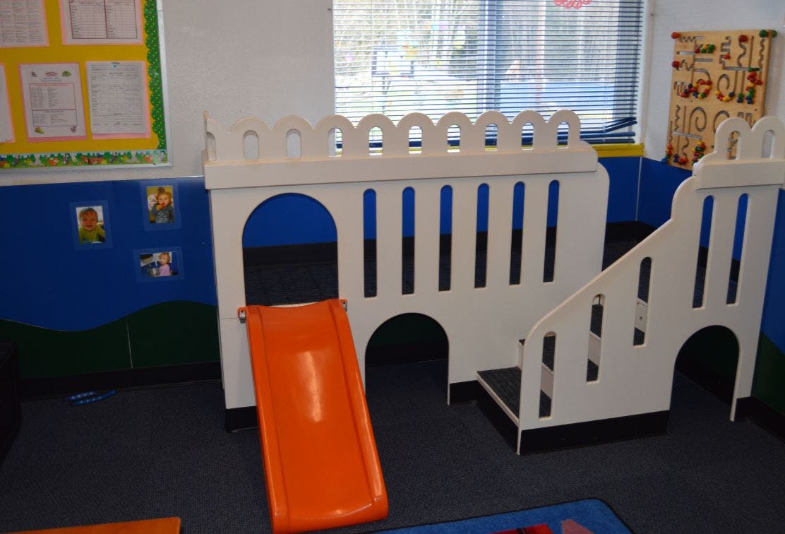 Indoor play structure with an orange slide and stairs