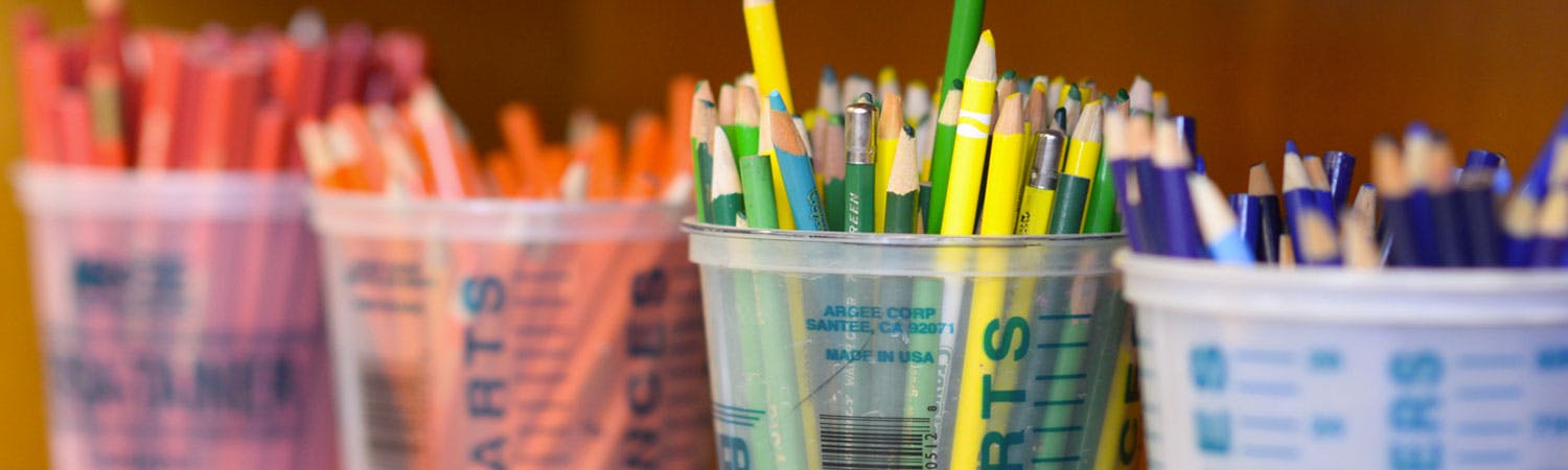 Multiple cups filled with colored pencils and art supplies