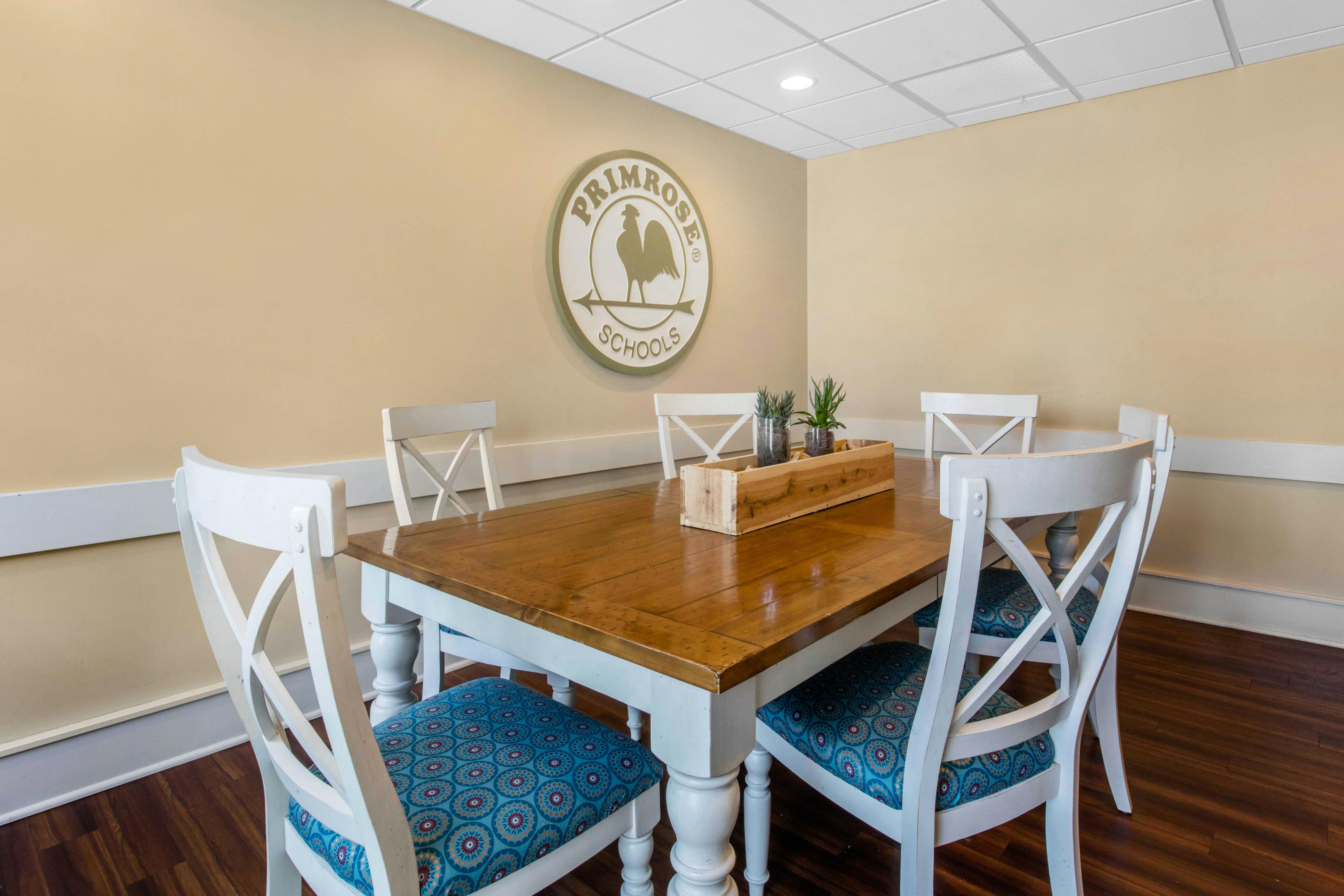 Dining room with a table, four chairs, and a Primrose Schools logo on the wall