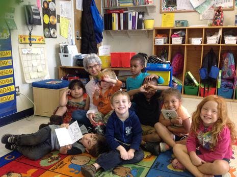 Adult and multiple children sitting on a rug in a classroom