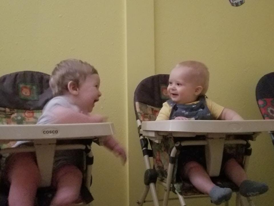 Two babies sitting in high chairs facing each other