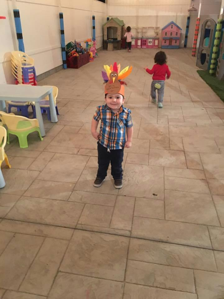 Child wearing a turkey hat standing in a room