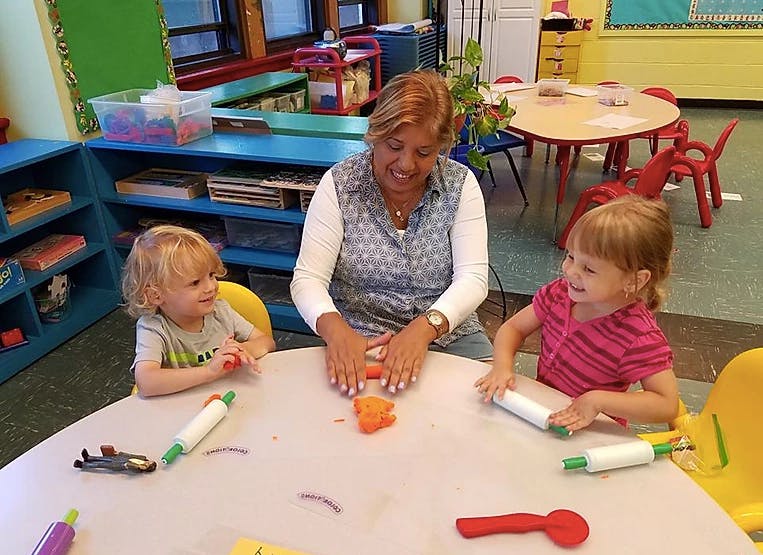 Adult and two children playing with modeling clay at a table