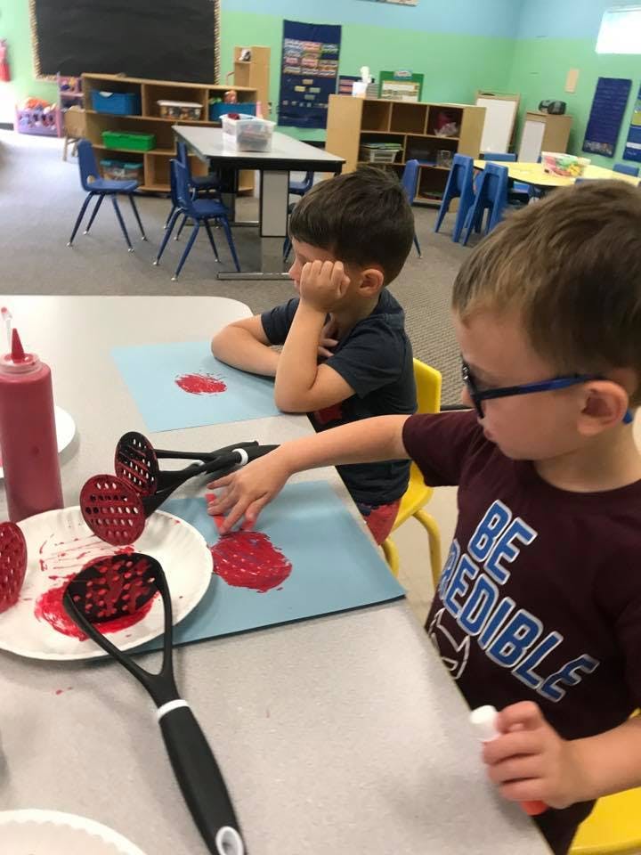 Two children doing an art project with red paint