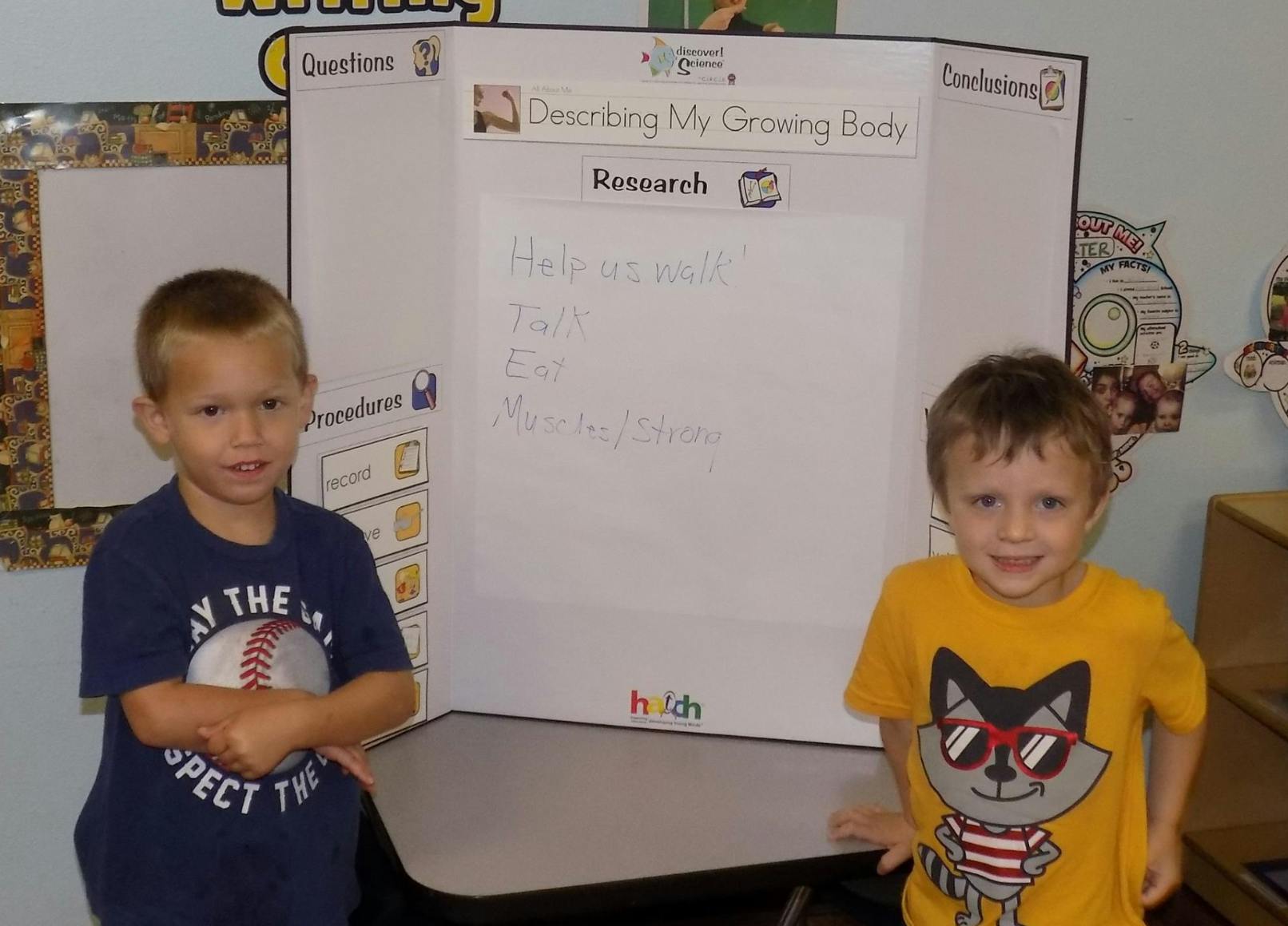 Two children standing in front of a science project board