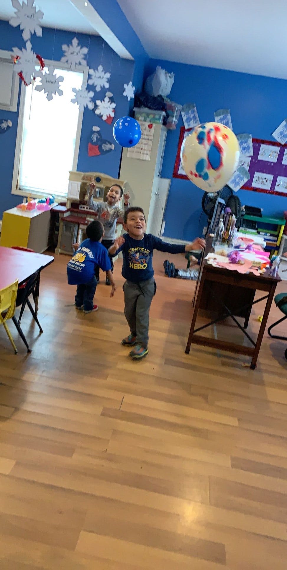 Three children playing with balloons in a room