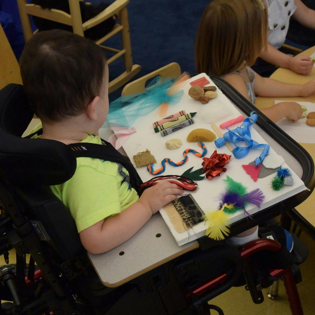 Child in a wheelchair interacting with a sensory board