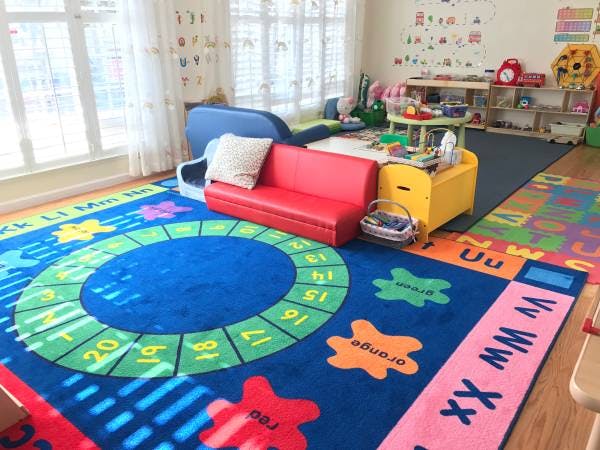 Playroom with colorful alphabet and number rug, red couch, and toys