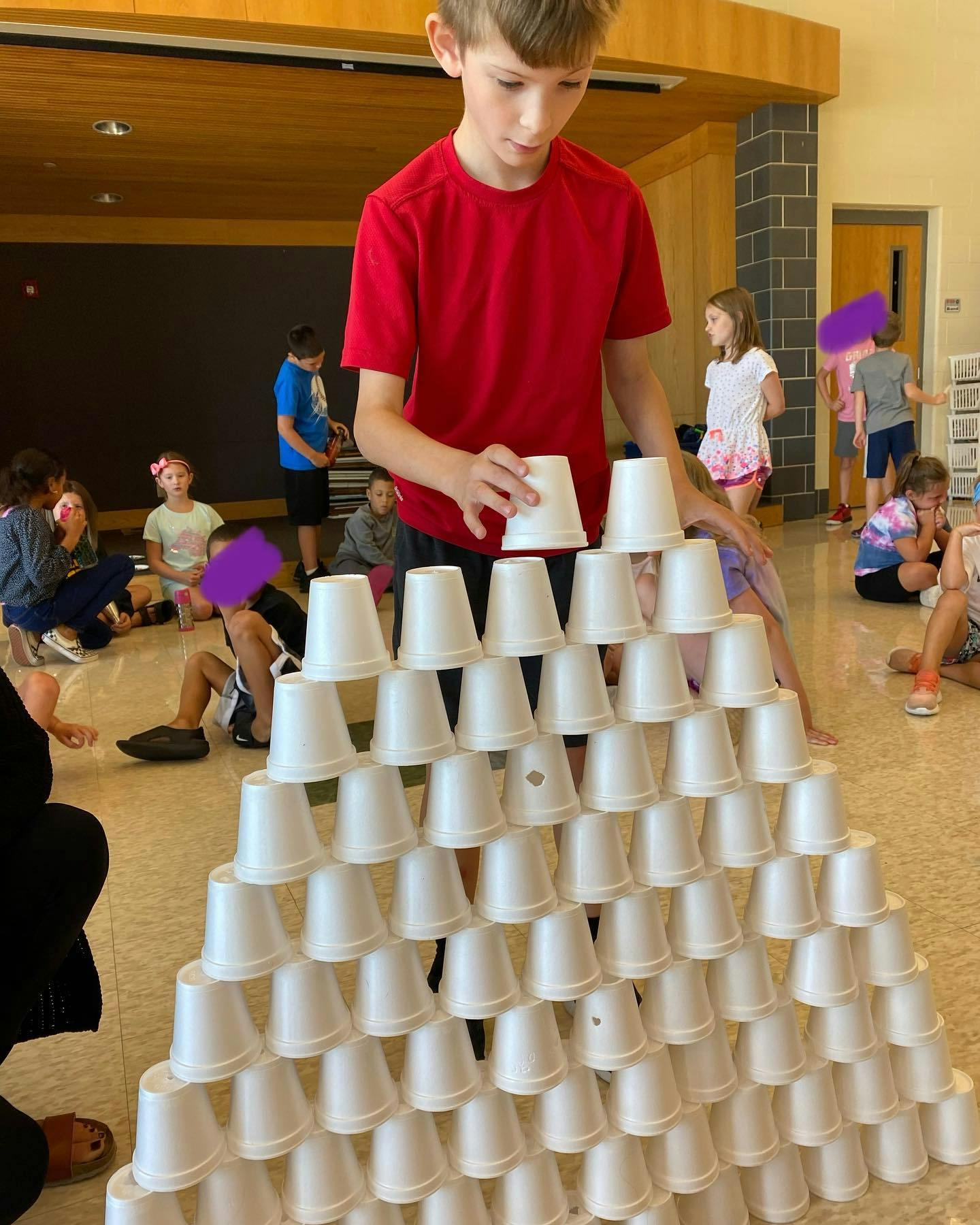 Child building a pyramid with white plastic cups