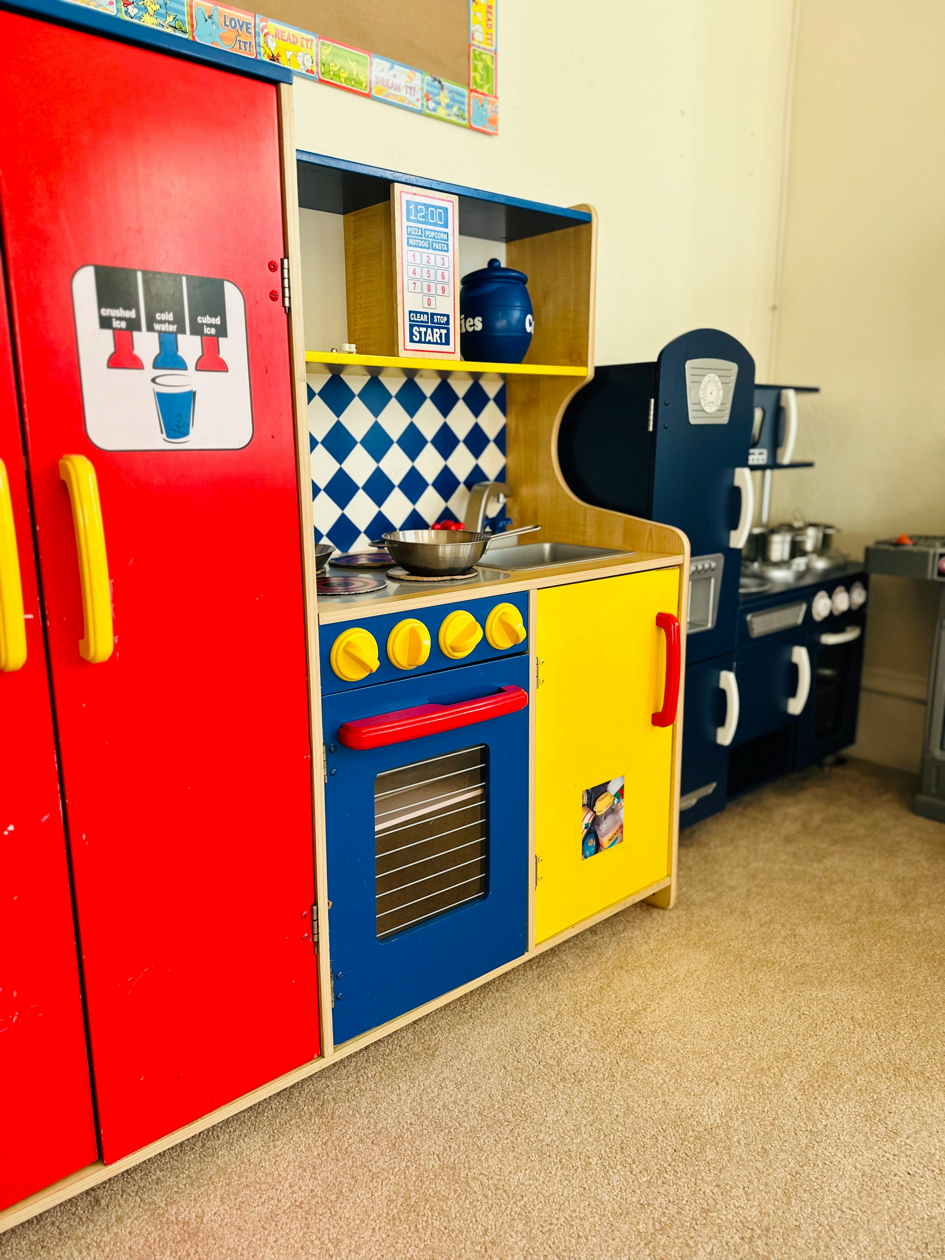 Colorful toy kitchen set with a red refrigerator and blue and yellow stove