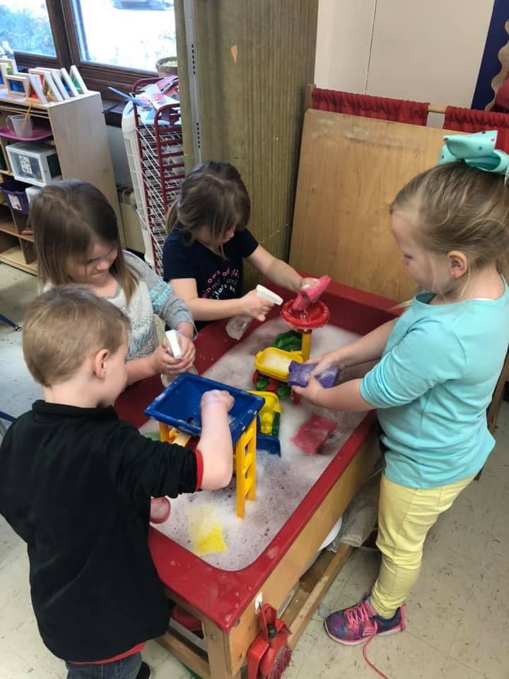 Four children playing with toys in a water table