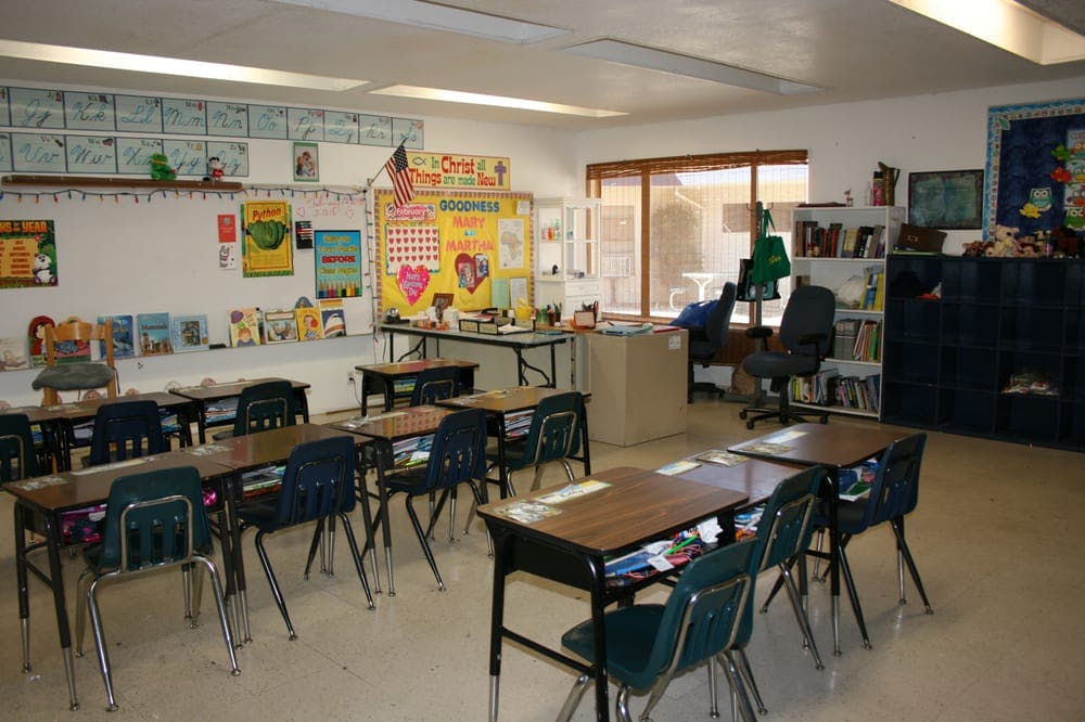 Empty classroom with desks and chairs facing a whiteboard