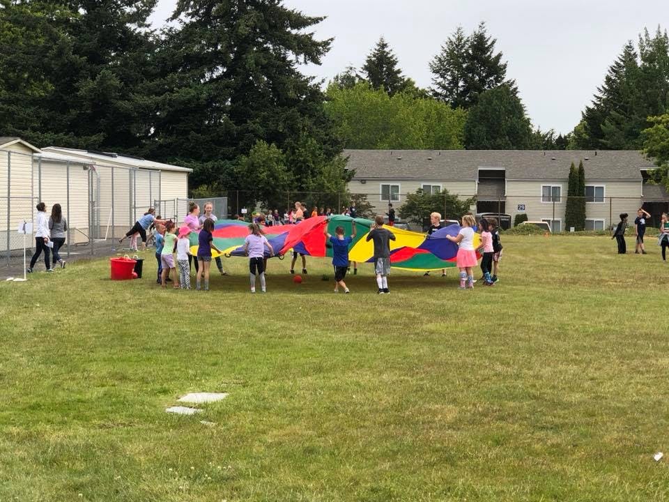 Children playing with a colorful parachute on a grassy field