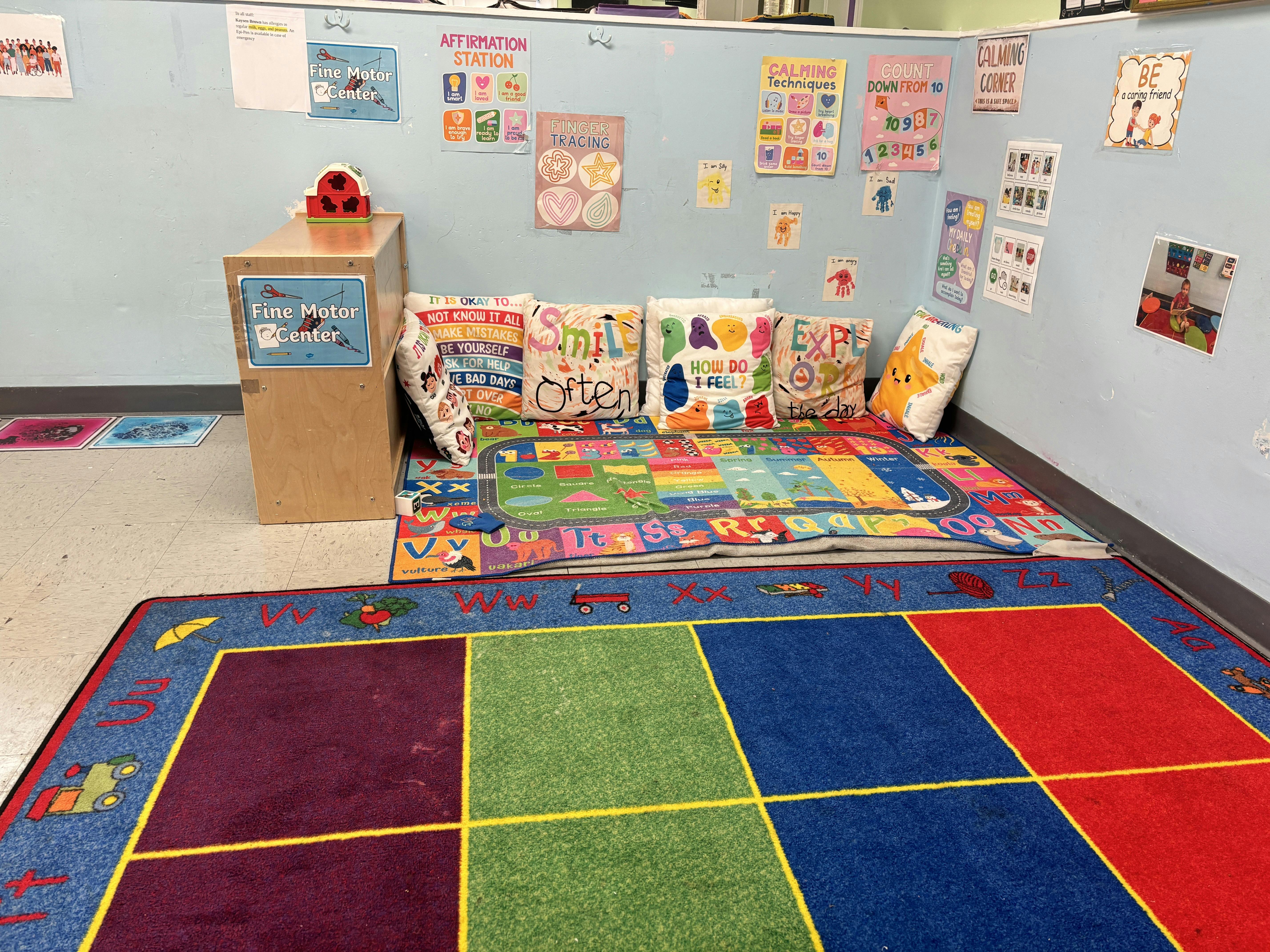 Classroom corner with educational posters and floor rugs with alphabet patterns
