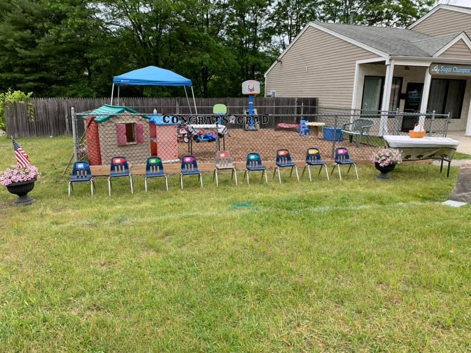 Outdoor play area with small chairs, playhouse, and blue canopy