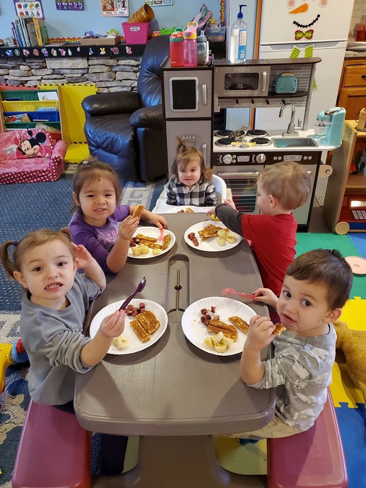 Four children eating at a table in a classroom
