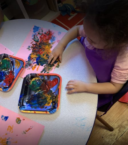 Child finger painting on paper at a table