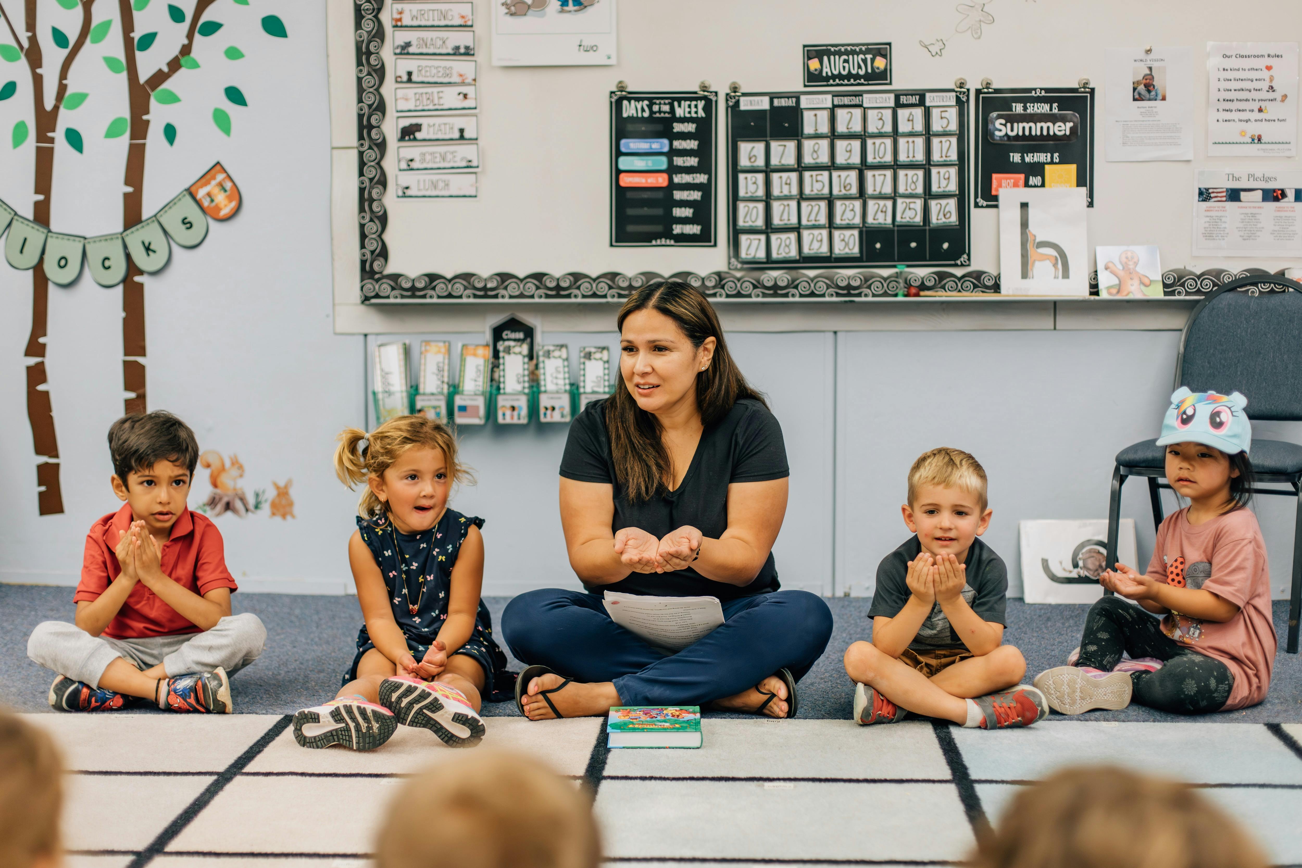 Adult and three children sitting on floor in classroom
