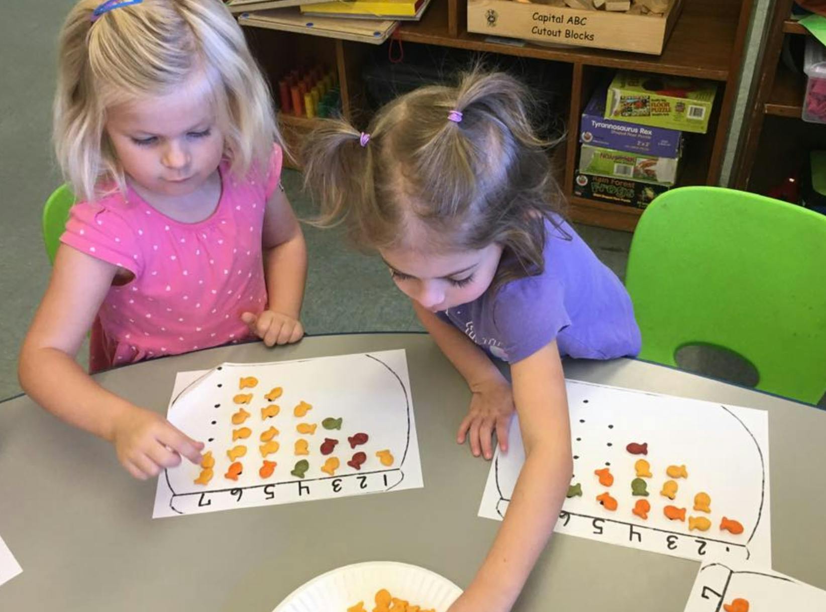 Two children sorting colorful candy on counting sheets