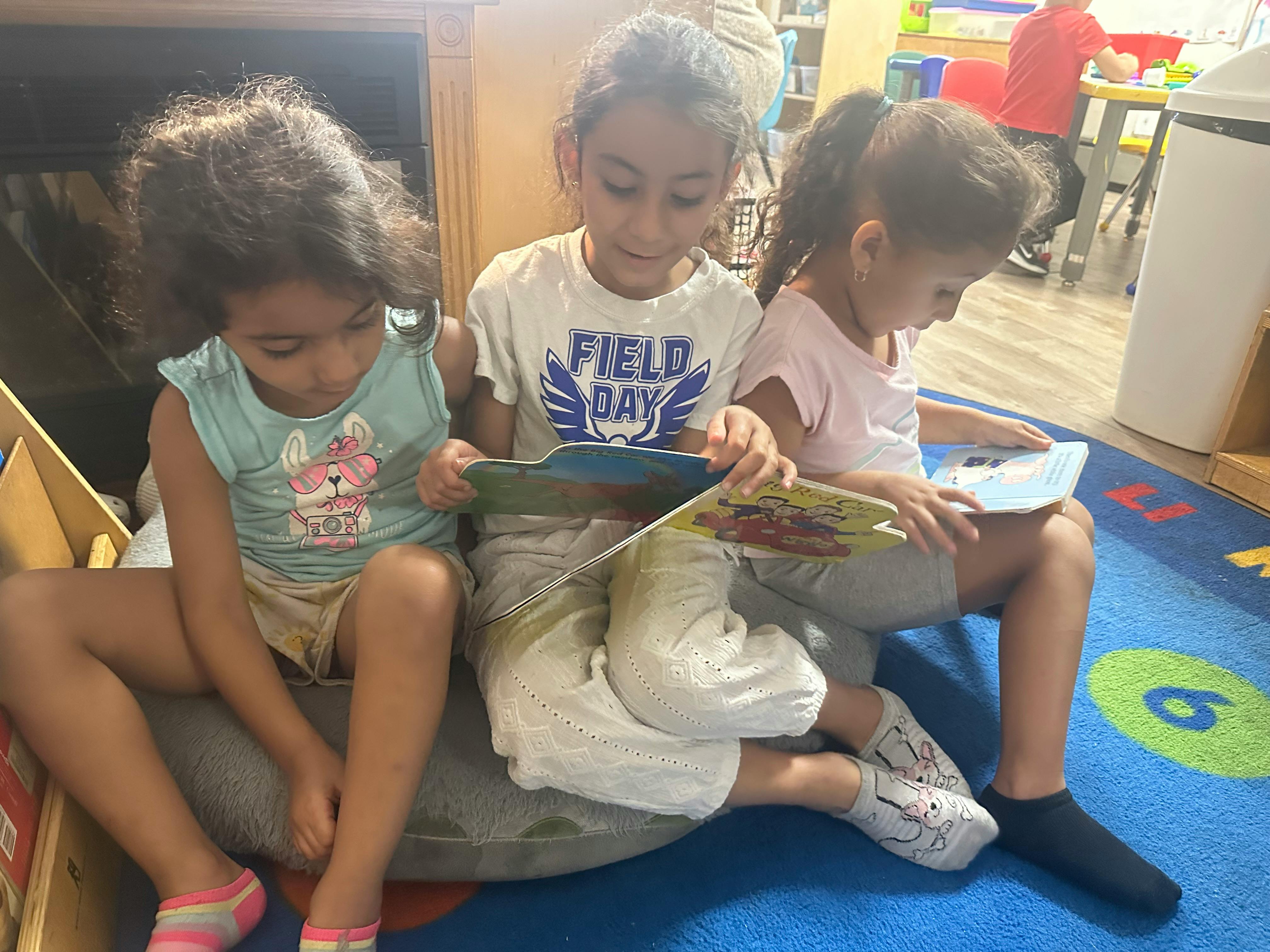 Three children sitting on the floor reading books