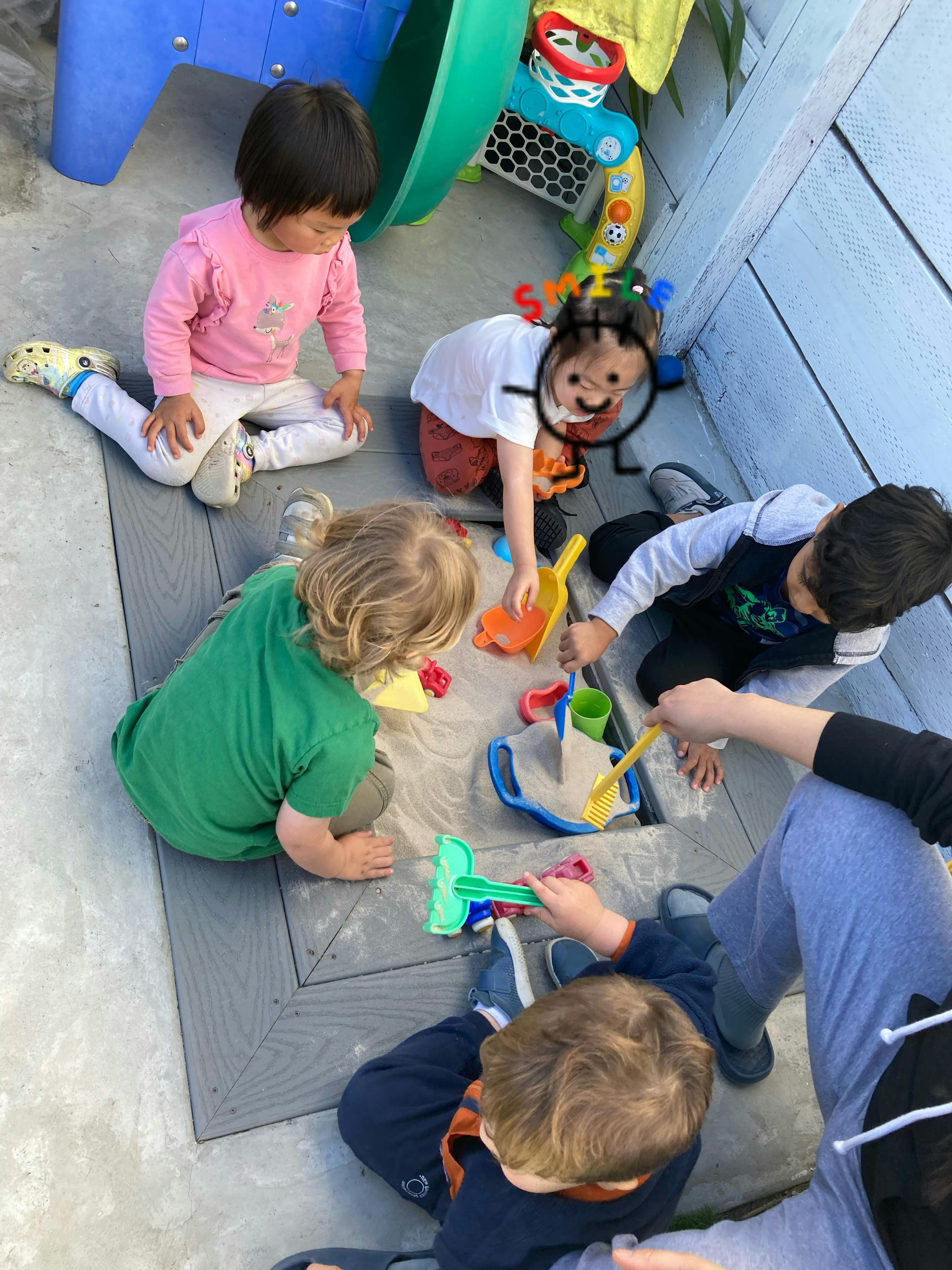 Children playing in a sandbox with toys