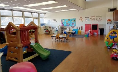 Indoor playground with slide and tables in a classroom