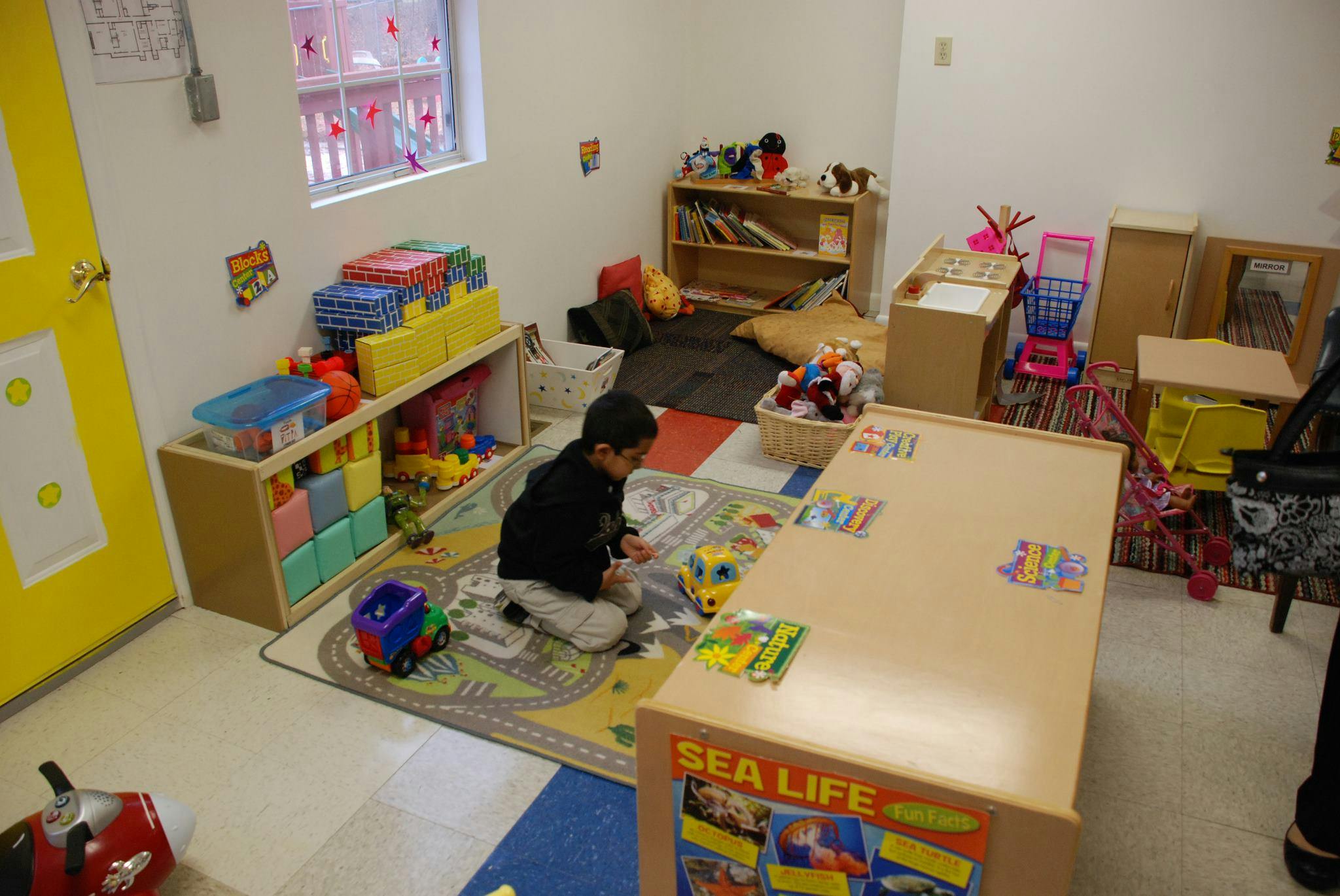Child playing on a rug in a classroom