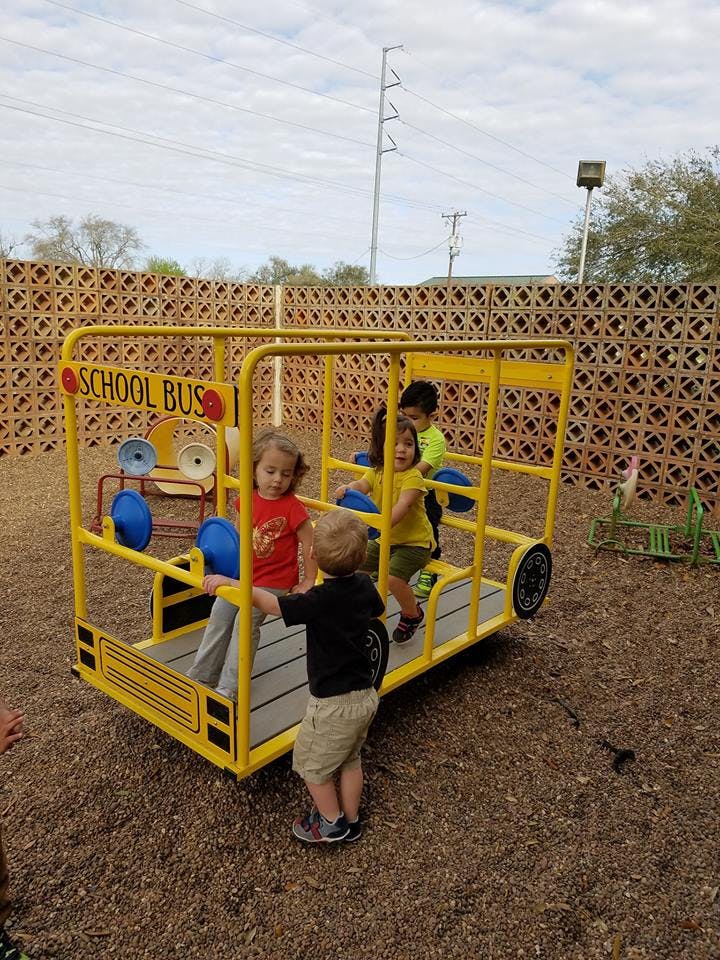 Children playing on a yellow school bus playground structure