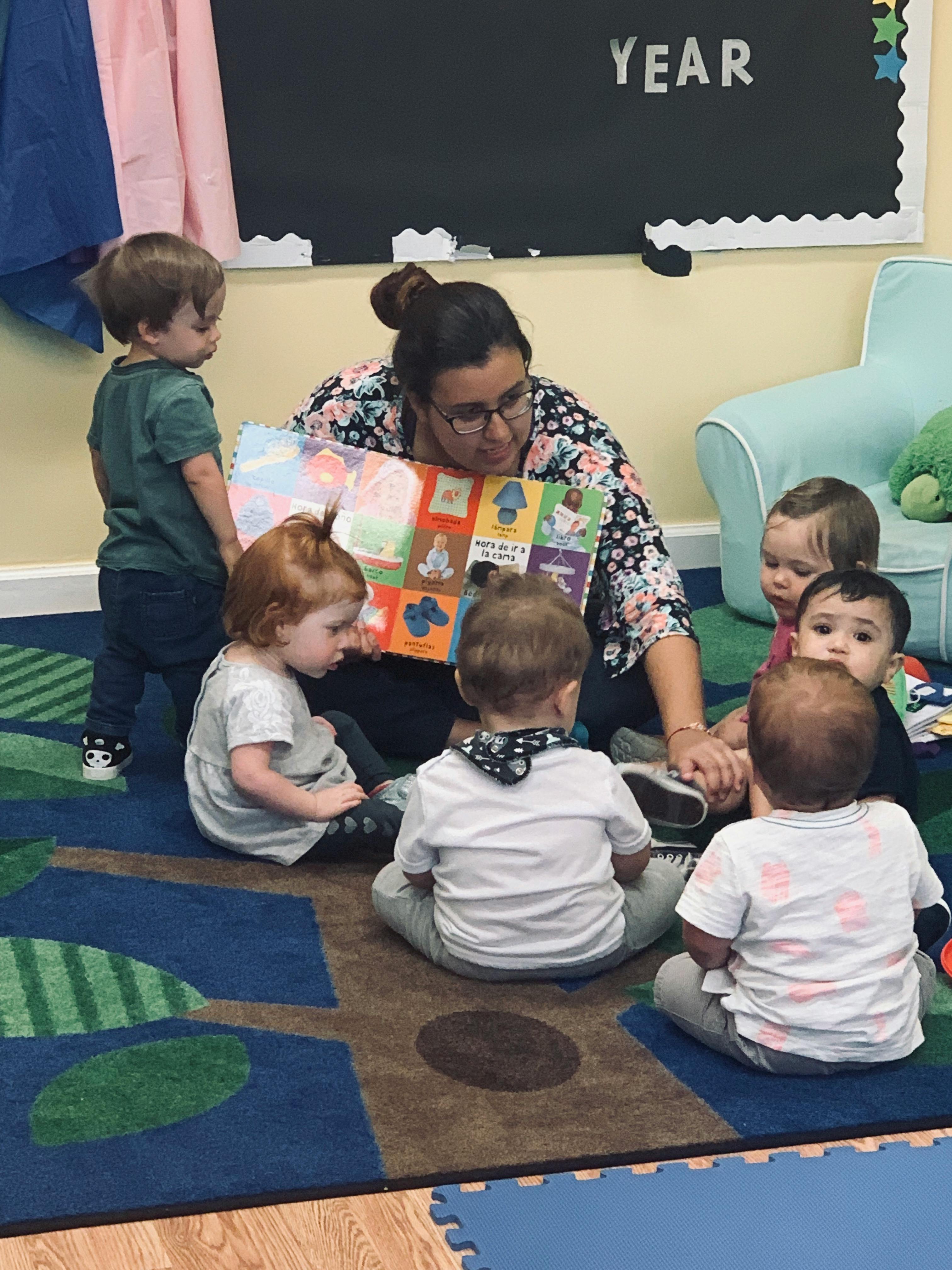 Person reading a book to a group of children in a classroom