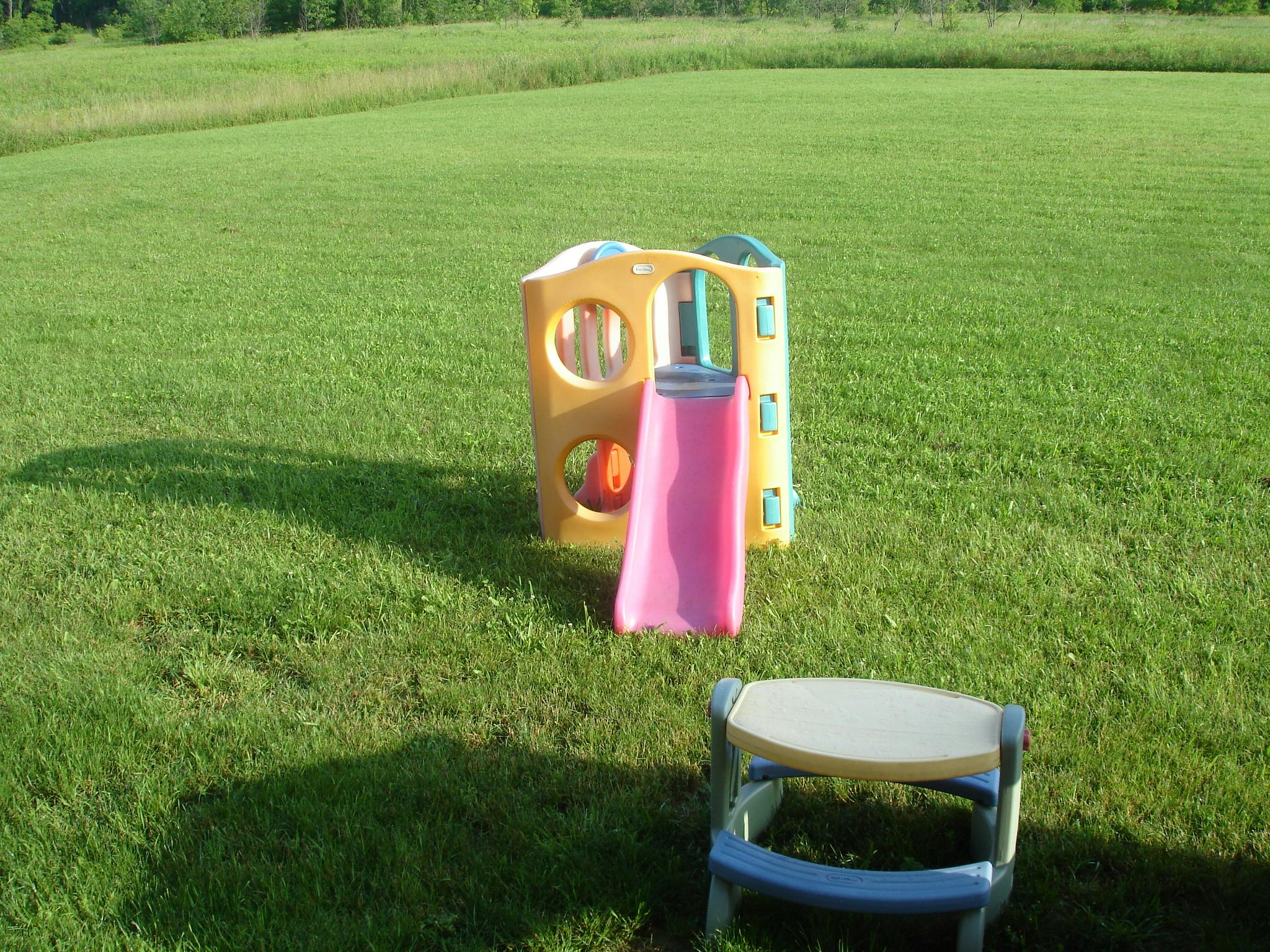 Child's play structure with slide and small stool on grass