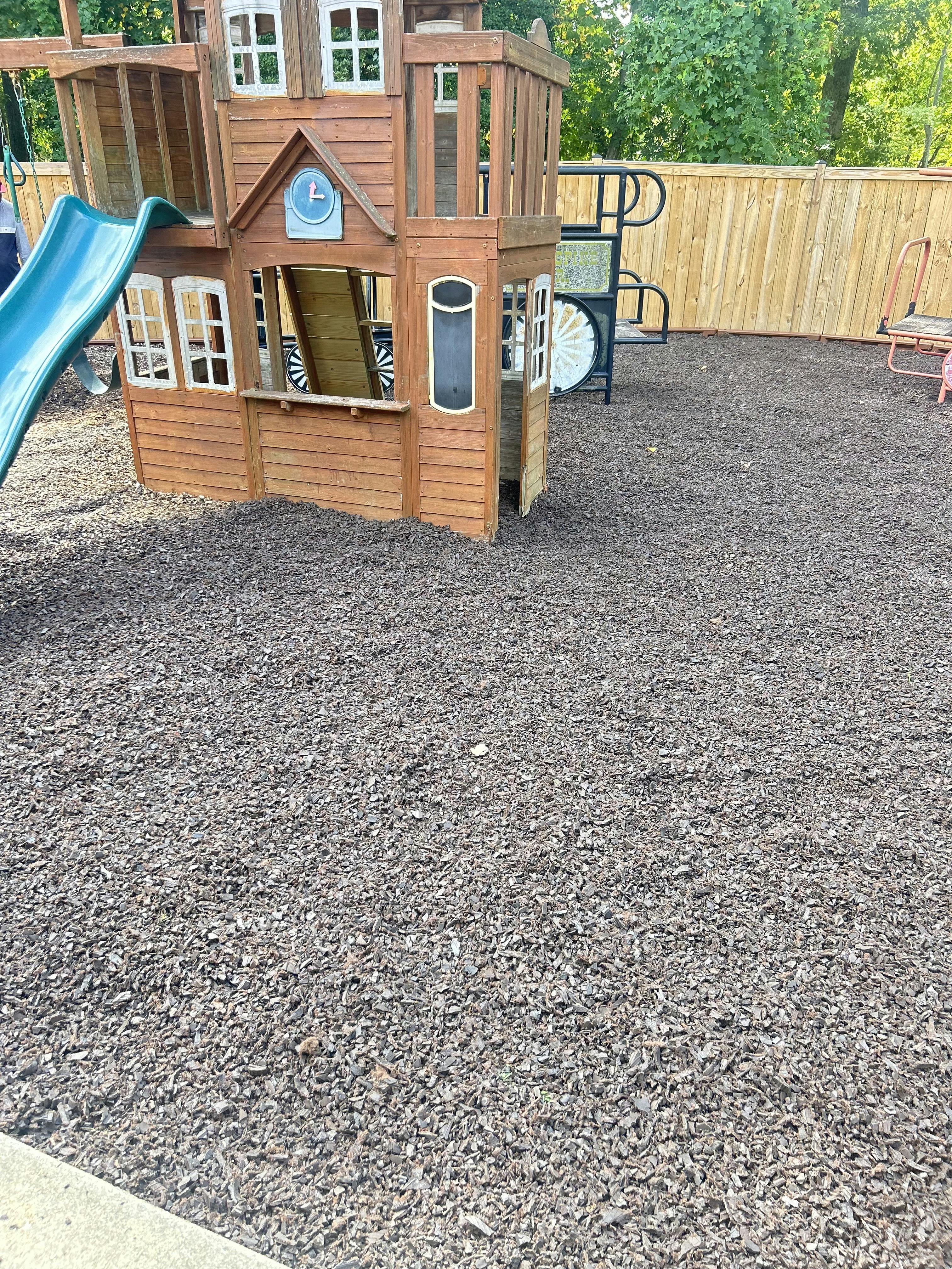 Wooden playground with a blue slide on a ground of dark wood chips