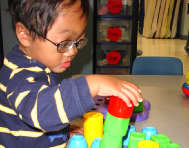 Child wearing glasses playing with colorful stacking toys