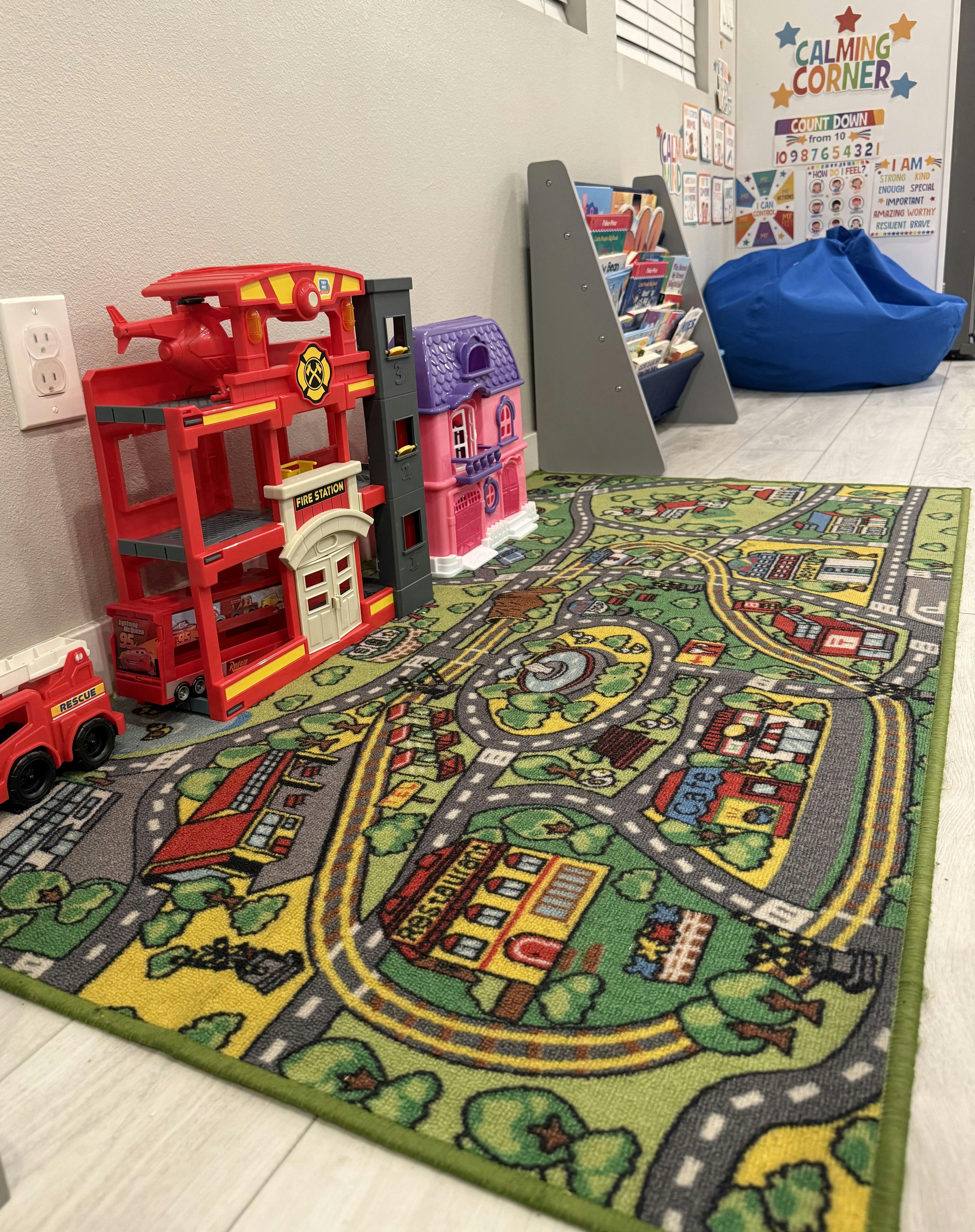 Toy fire station and dollhouse on a city map play rug in a playroom