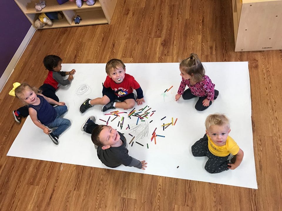 Multiple children playing with colorful blocks on a white mat