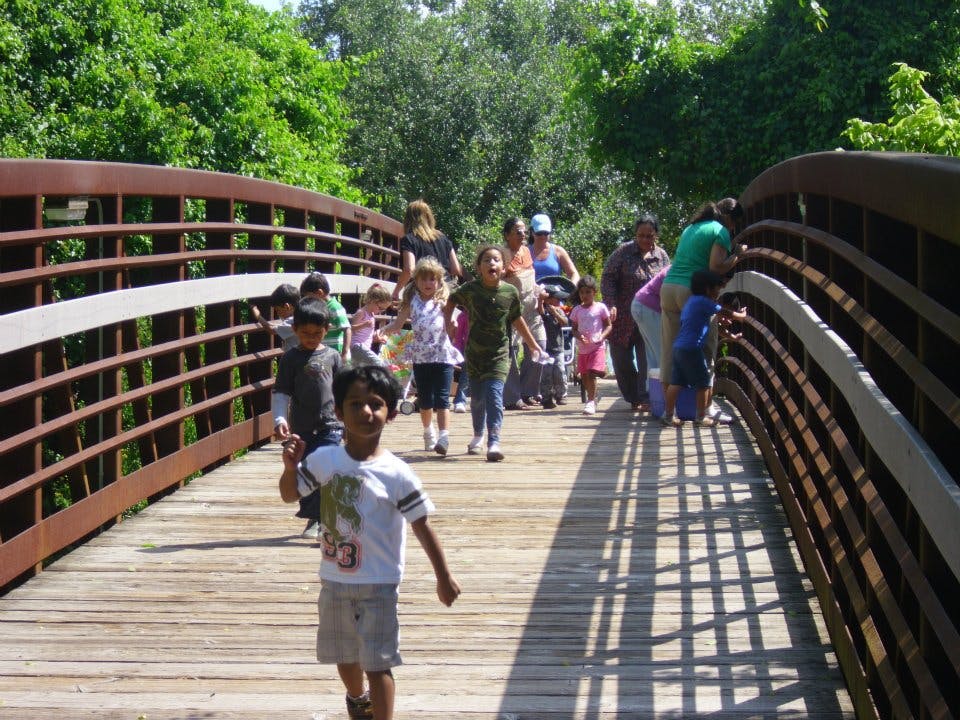 People and children walking on a wooden bridge