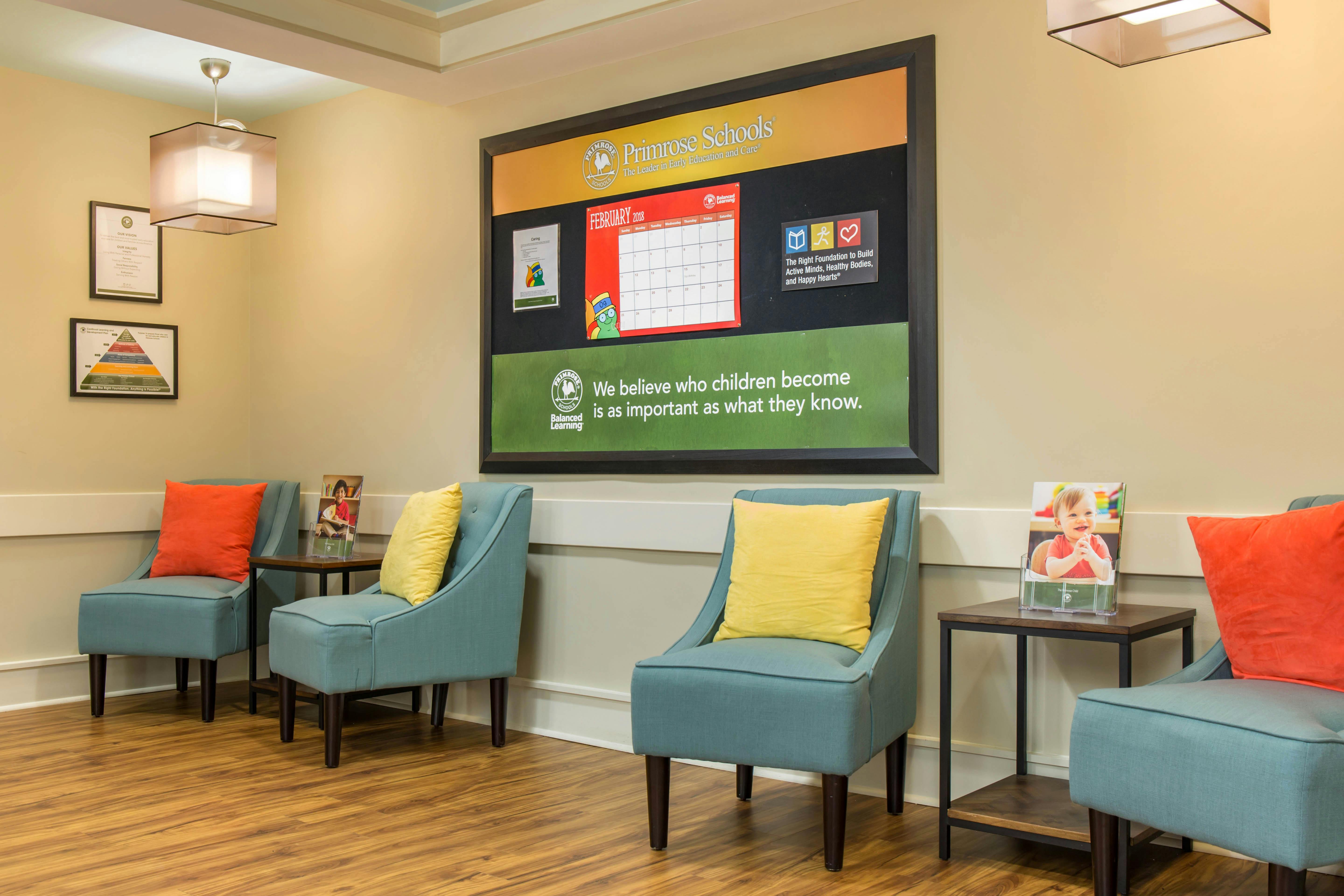 lobby area with a wall sign from Primrose Schools and teal chairs with colorful pillows
